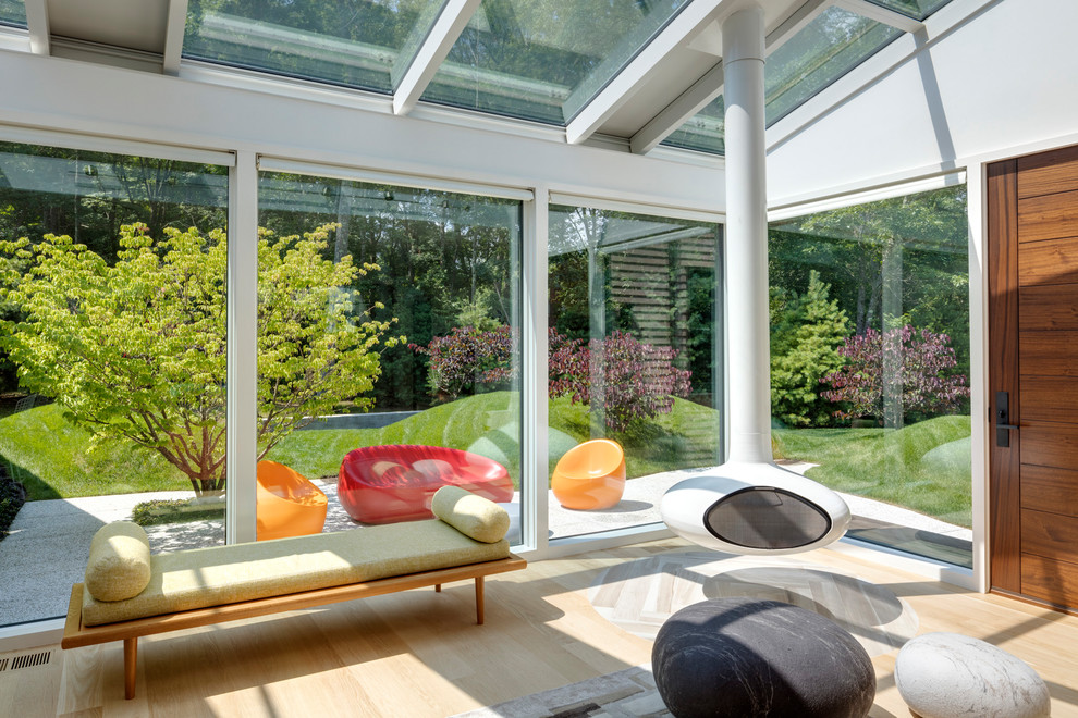 Foto di una veranda minimal di medie dimensioni con parquet chiaro, camino sospeso e lucernario