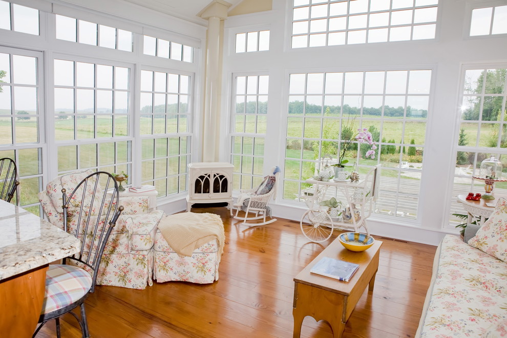 This is an example of a farmhouse conservatory in Other with medium hardwood flooring and a wood burning stove.