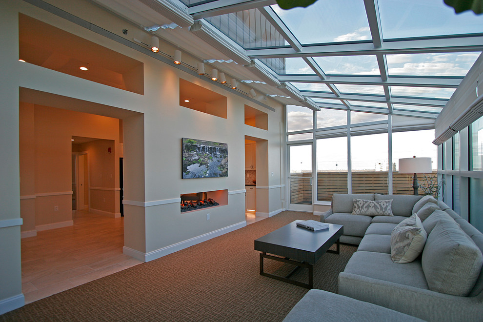На фото: большая терраса в стиле неоклассика (современная классика) с ковровым покрытием, двусторонним камином, потолочным окном и коричневым полом с