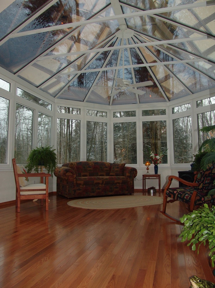 Aménagement d'une grande véranda classique avec un sol en bois brun, aucune cheminée et un plafond en verre.