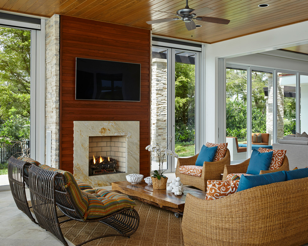 Idee per una veranda tropicale con camino classico, cornice del camino in pietra, soffitto classico e pavimento beige