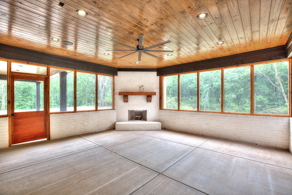 Foto på ett vintage uterum, med betonggolv, en öppen hörnspis, en spiselkrans i tegelsten och grått golv