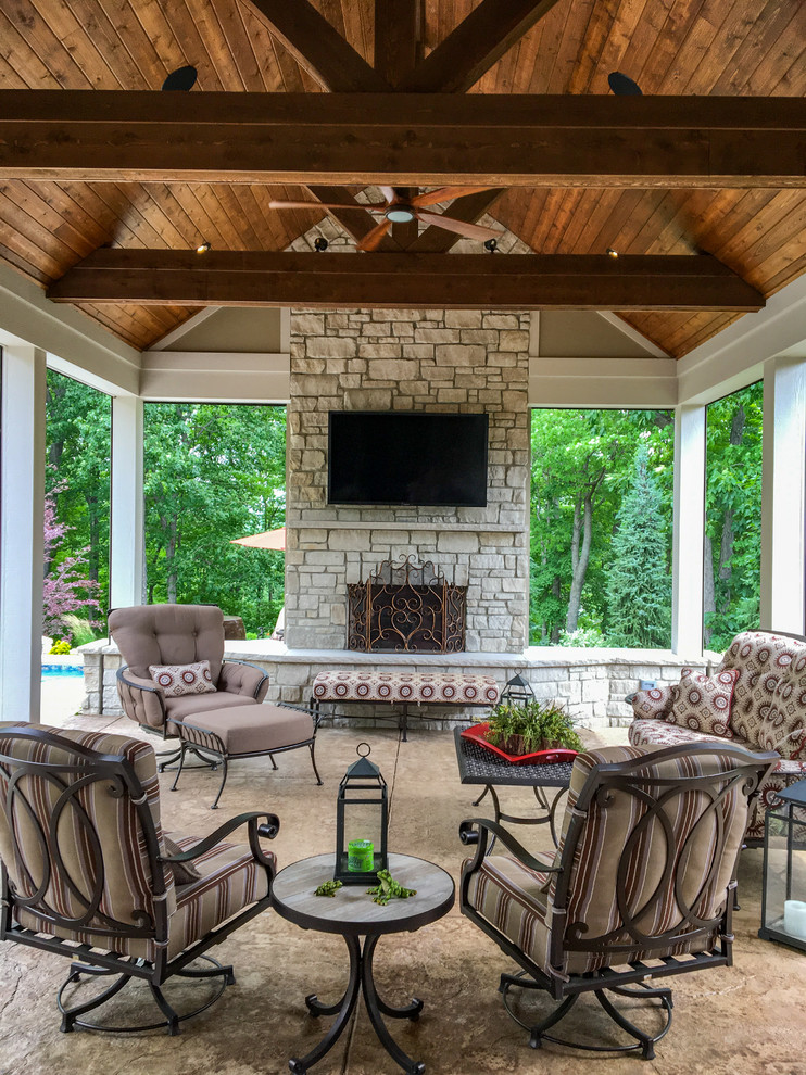 Photo of a large conservatory in St Louis with concrete flooring, a standard fireplace, a stone fireplace surround, a standard ceiling and brown floors.