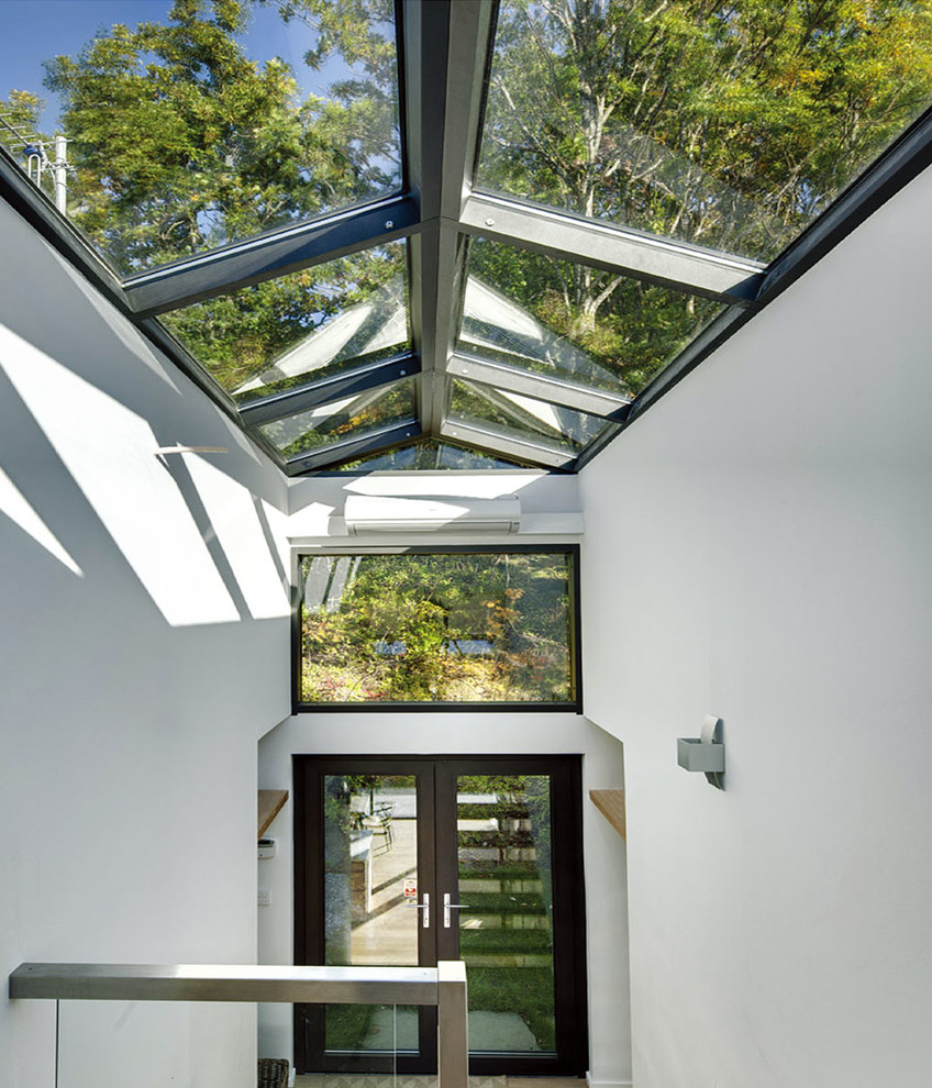 Immagine di una grande veranda moderna con parquet chiaro, camino classico e soffitto in vetro