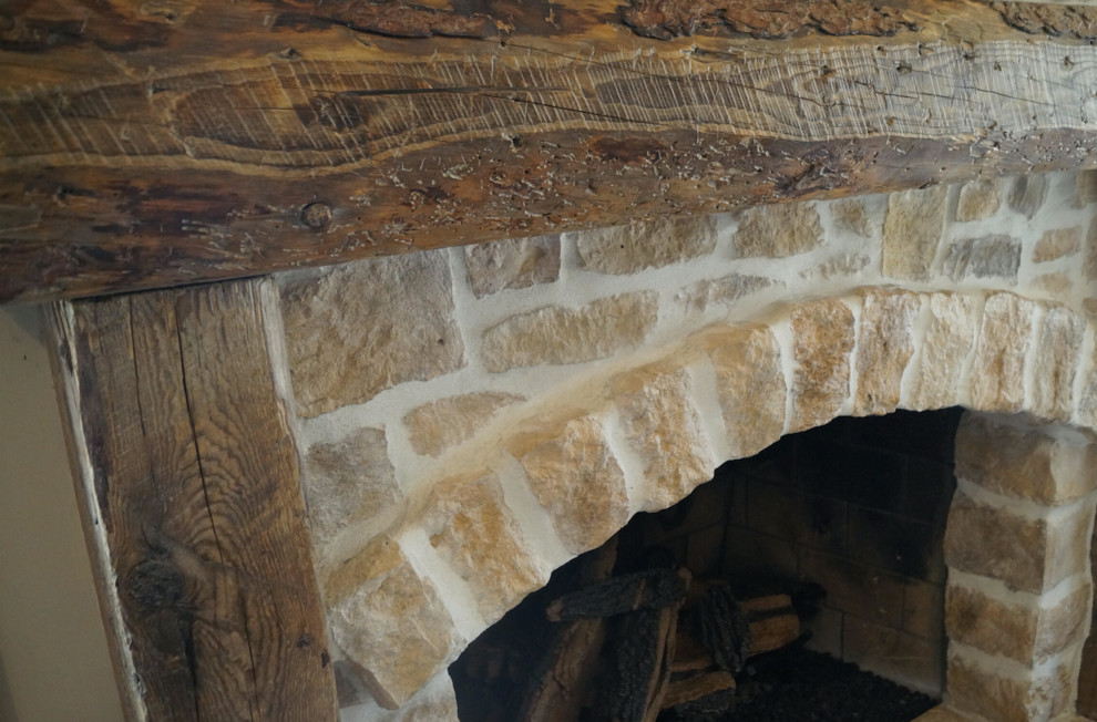 Inspiration pour une véranda chalet de taille moyenne avec un sol en bois brun, une cheminée standard, un manteau de cheminée en pierre et un plafond standard.