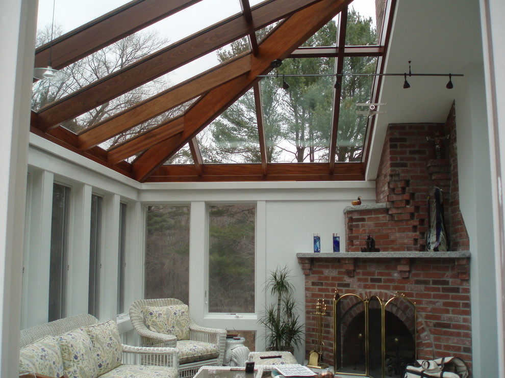 Idee per una veranda contemporanea di medie dimensioni con camino ad angolo, cornice del camino in mattoni e soffitto in vetro