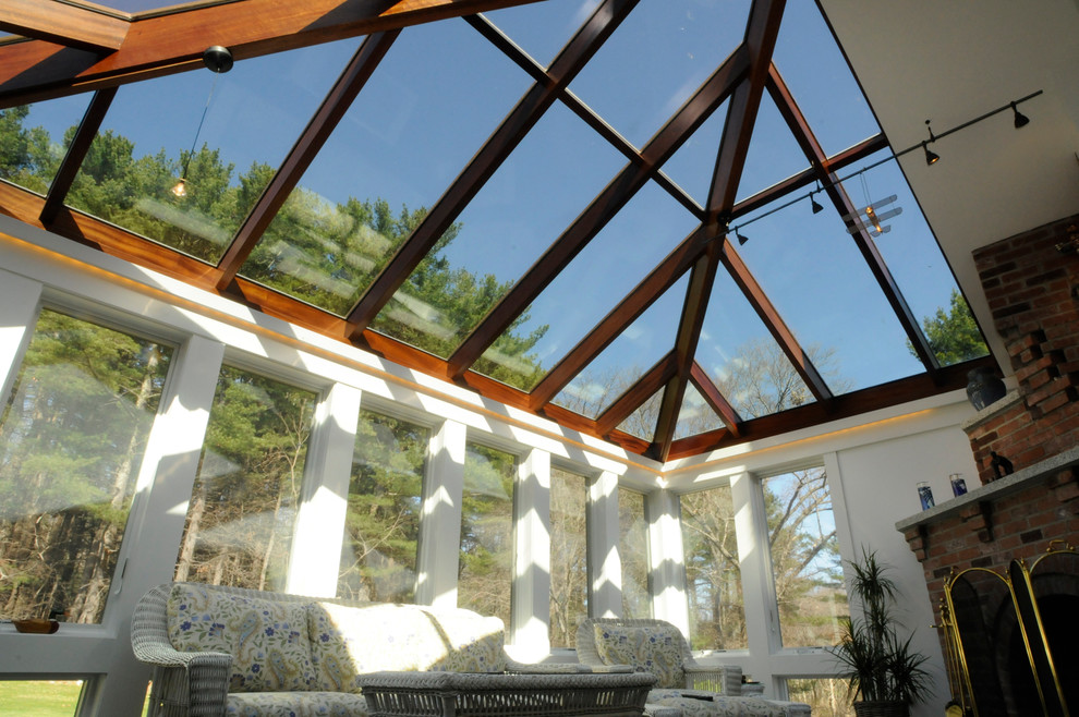 Immagine di una veranda contemporanea di medie dimensioni con camino ad angolo, cornice del camino in mattoni e soffitto in vetro