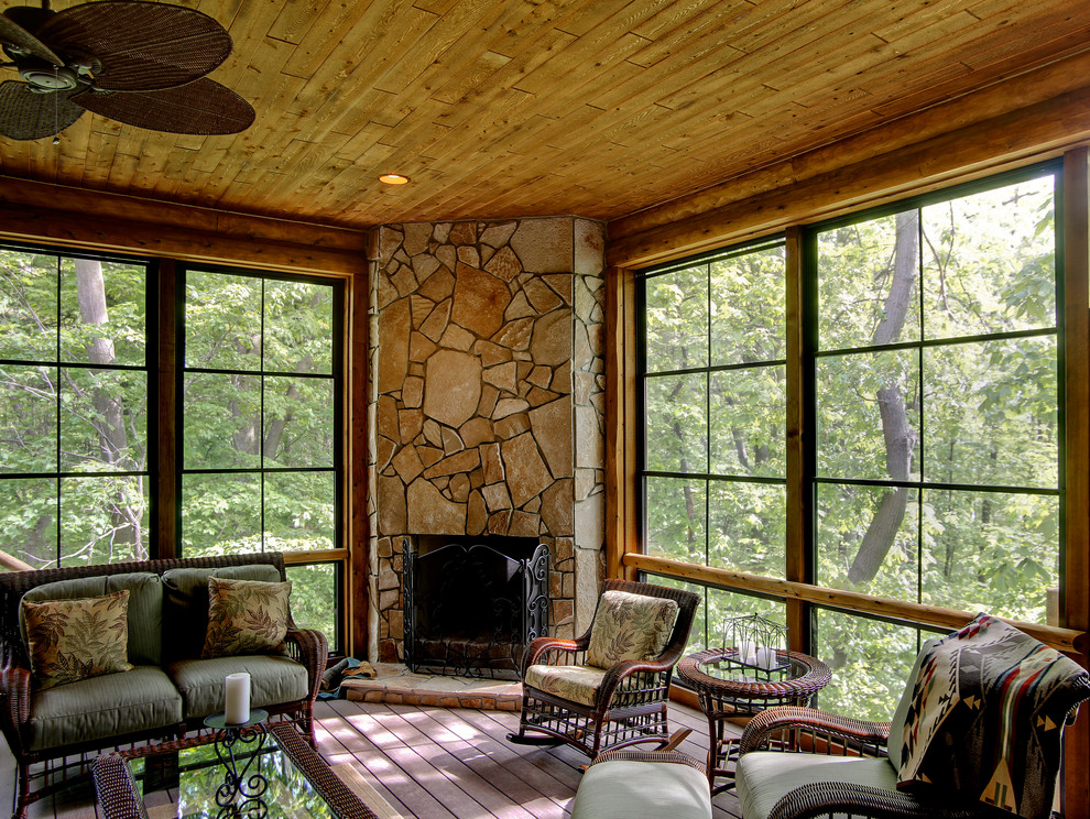 Aménagement d'une véranda montagne de taille moyenne avec un sol en bois brun, une cheminée standard, un manteau de cheminée en pierre, un plafond standard et un sol beige.
