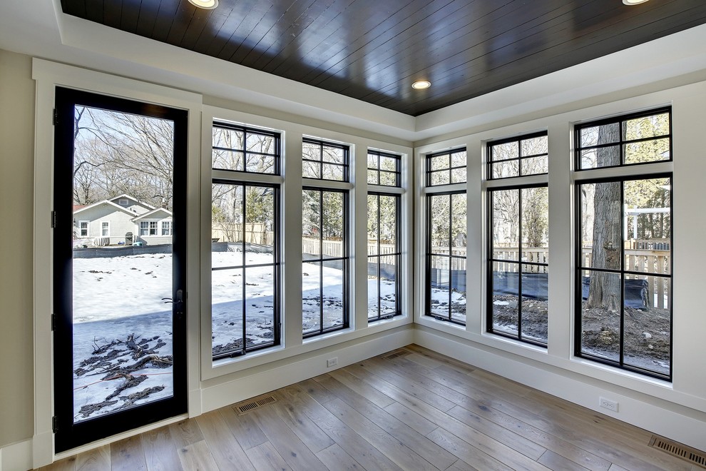 Medium sized farmhouse conservatory in Minneapolis with light hardwood flooring and a standard ceiling.