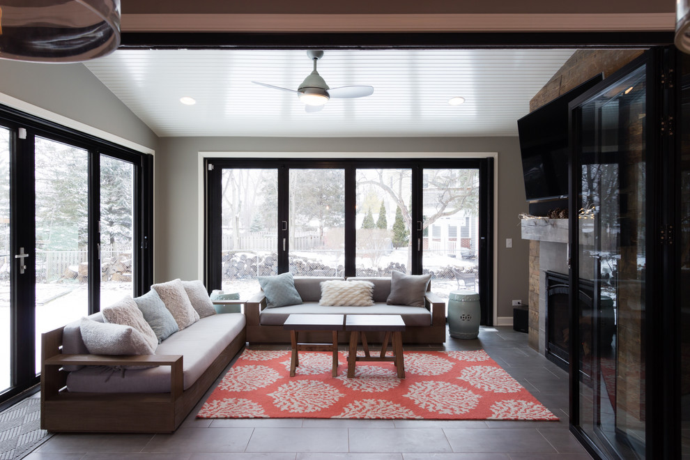 Idee per una grande veranda minimalista con pavimento in gres porcellanato, camino classico, cornice del camino piastrellata, soffitto classico e pavimento grigio