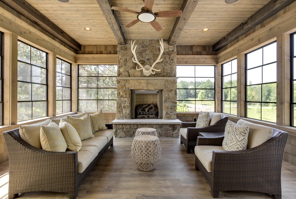 Mid-sized mountain style medium tone wood floor and gray floor sunroom photo in Minneapolis with a standard fireplace, a standard ceiling and a stone fireplace