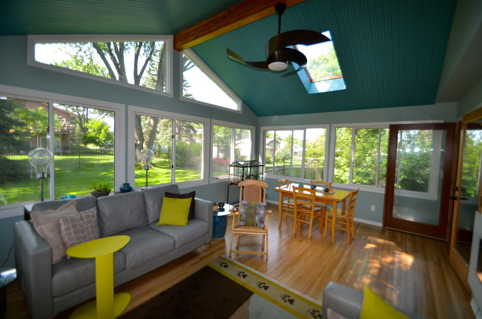 Immagine di una veranda design con parquet chiaro, camino sospeso e lucernario