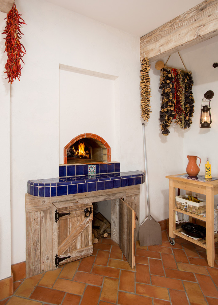 Foto på ett medelhavsstil uterum, med klinkergolv i terrakotta, en öppen vedspis, en spiselkrans i trä, tak och orange golv