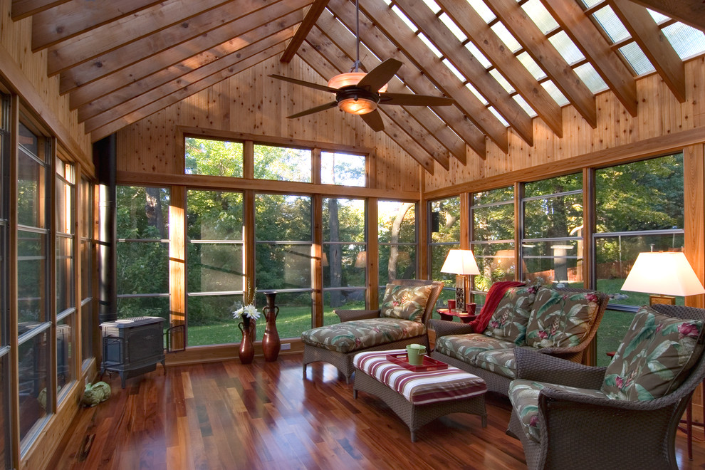 Immagine di una veranda stile rurale di medie dimensioni con parquet scuro, stufa a legna e soffitto in vetro
