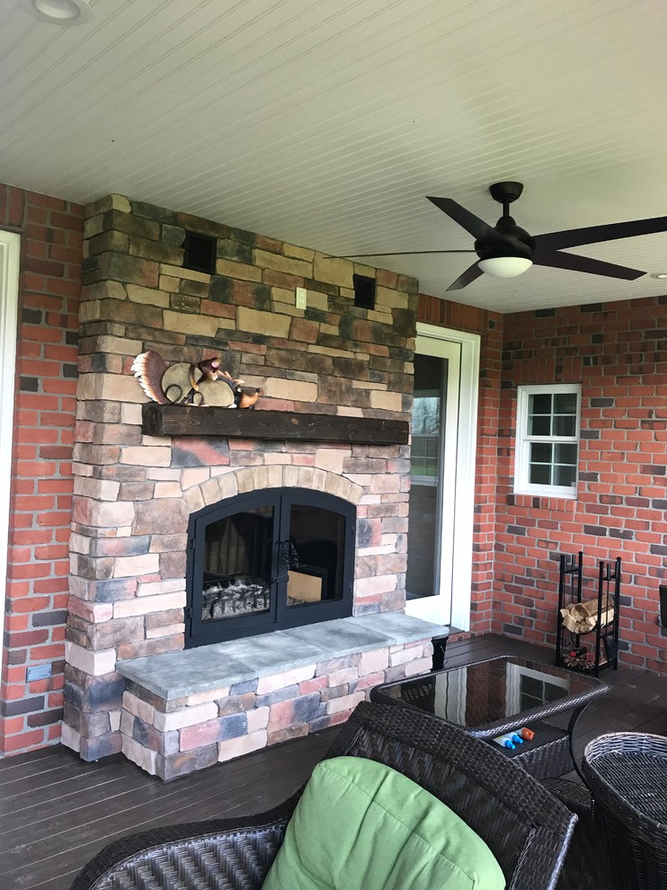 Inspiration for a large country dark wood floor and brown floor sunroom remodel in Kansas City with a two-sided fireplace, a brick fireplace and a standard ceiling