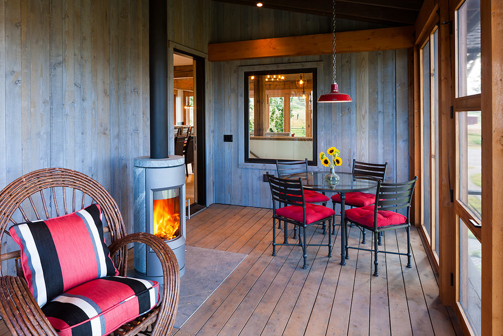 Immagine di una veranda stile rurale di medie dimensioni con parquet scuro, stufa a legna, cornice del camino in pietra e soffitto classico