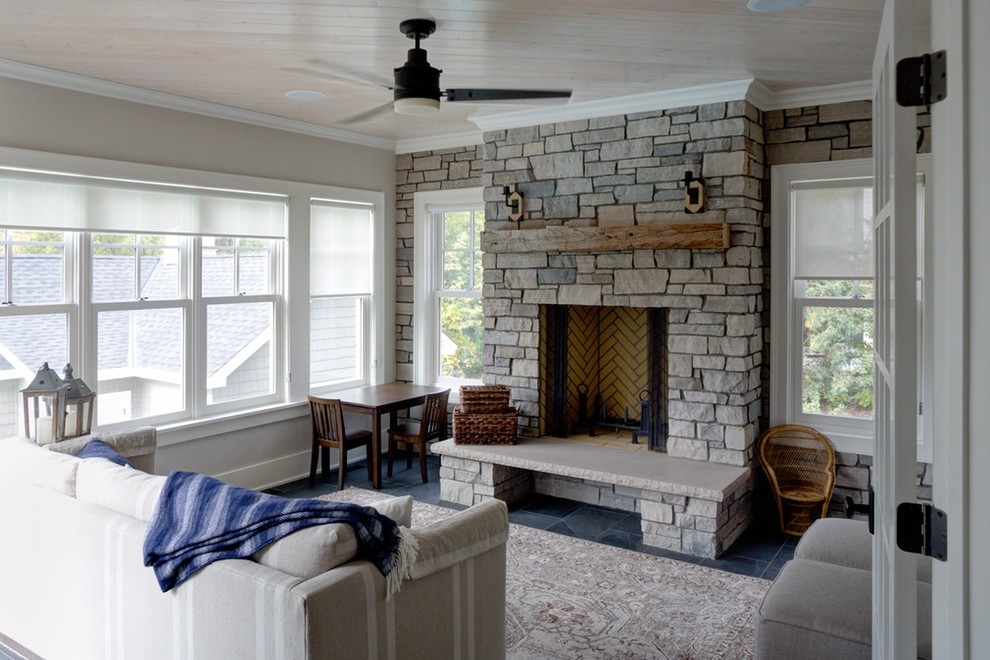 Cette image montre une véranda traditionnelle de taille moyenne avec une cheminée standard, un manteau de cheminée en pierre, un plafond standard, un sol en ardoise et un sol gris.