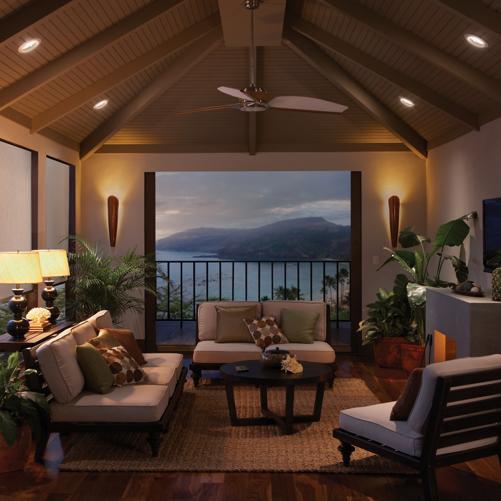 Immagine di una veranda tropicale di medie dimensioni con parquet scuro, camino classico, cornice del camino in pietra, soffitto classico e pavimento marrone