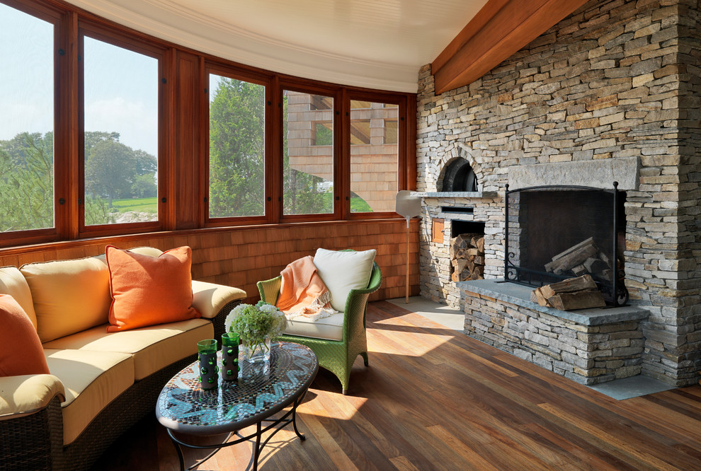 Ispirazione per una veranda american style con pavimento in legno massello medio, cornice del camino in pietra e soffitto classico