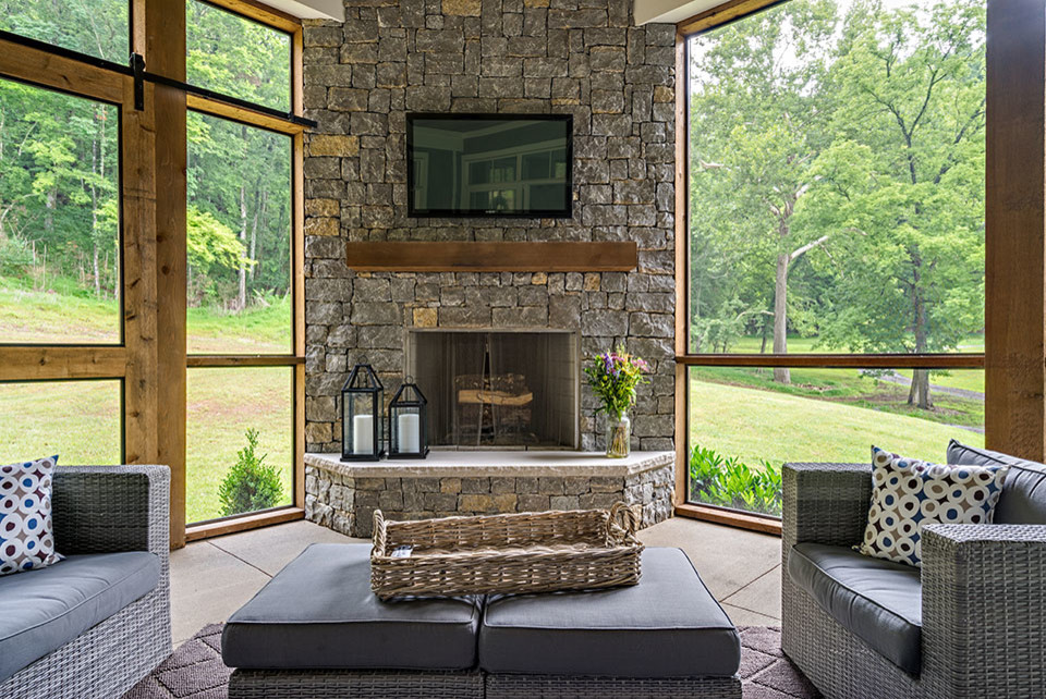 Cette image montre une véranda rustique de taille moyenne avec sol en béton ciré, une cheminée d'angle, un manteau de cheminée en pierre, un plafond standard et un sol beige.