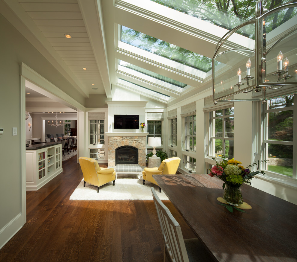 Example of a large transitional medium tone wood floor and brown floor sunroom design in Minneapolis with a stone fireplace, a skylight and a standard fireplace
