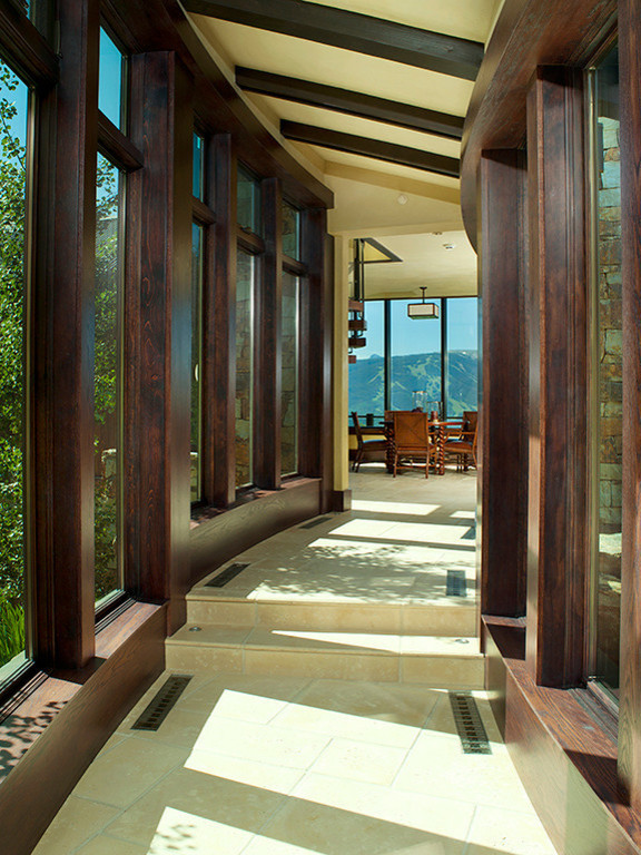 Immagine di una grande veranda design con pavimento in pietra calcarea, nessun camino e soffitto classico
