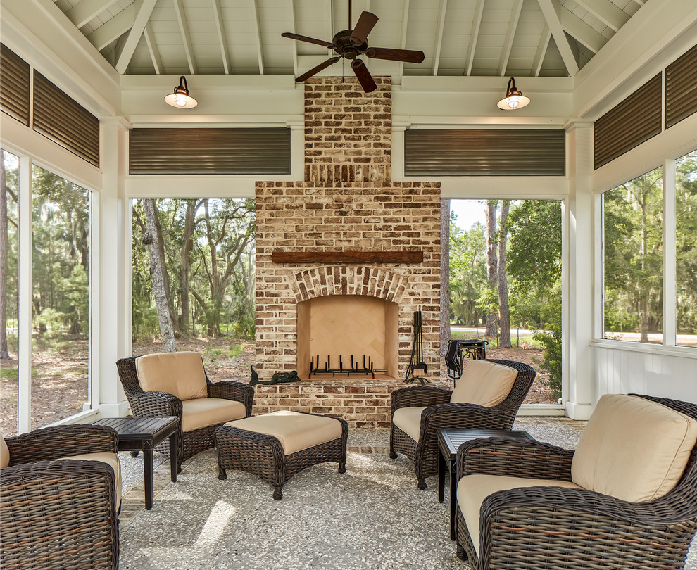 Cette image montre une grande véranda traditionnelle avec une cheminée standard, un manteau de cheminée en brique et un plafond standard.