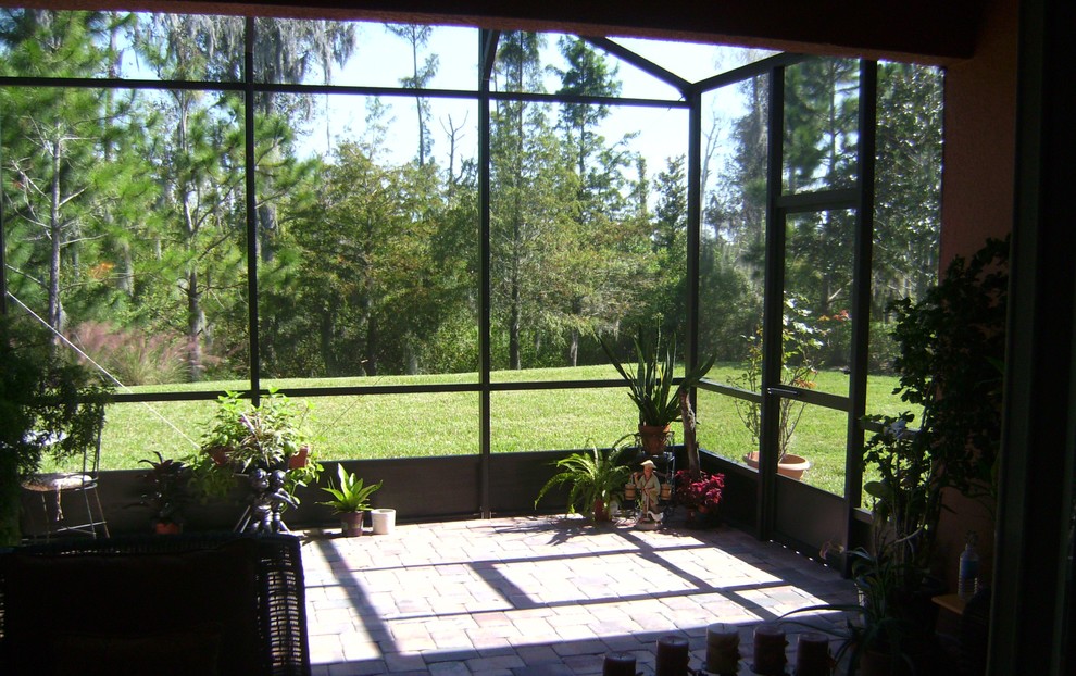 Esempio di una veranda contemporanea di medie dimensioni con pavimento in mattoni, nessun camino, soffitto in vetro e pavimento marrone