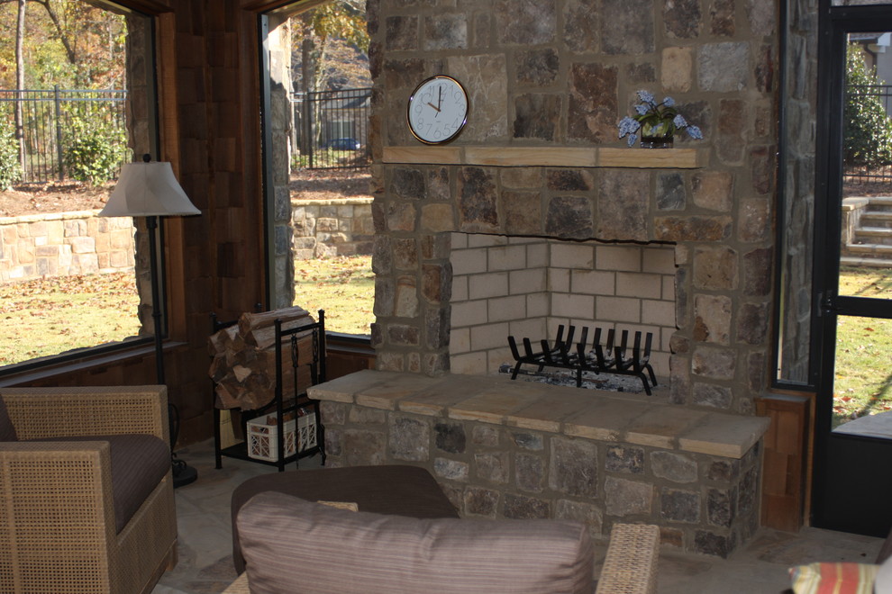 Réalisation d'une véranda chalet de taille moyenne avec sol en béton ciré, une cheminée standard, un manteau de cheminée en pierre, un plafond standard et un sol gris.