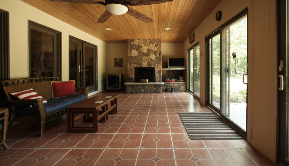 Foto di una grande veranda tradizionale con pavimento in terracotta, soffitto classico, pavimento arancione, camino classico e cornice del camino in pietra