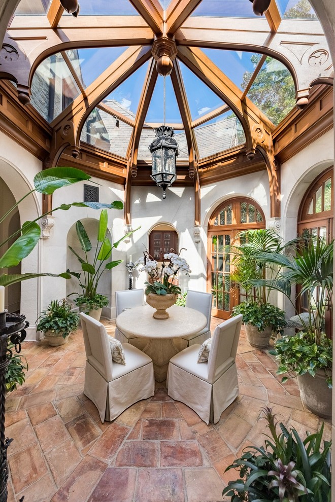 Inspiration for a mediterranean conservatory in Atlanta with terracotta flooring, a glass ceiling, brown floors and feature lighting.