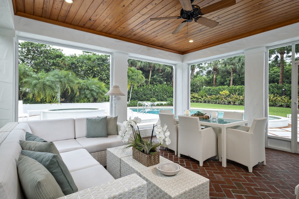 This is an example of a classic conservatory in Miami with brick flooring, a standard ceiling and brown floors.
