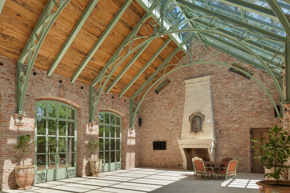 Inspiration pour une grande véranda urbaine avec sol en béton ciré, une cheminée standard, un manteau de cheminée en pierre et un plafond en verre.