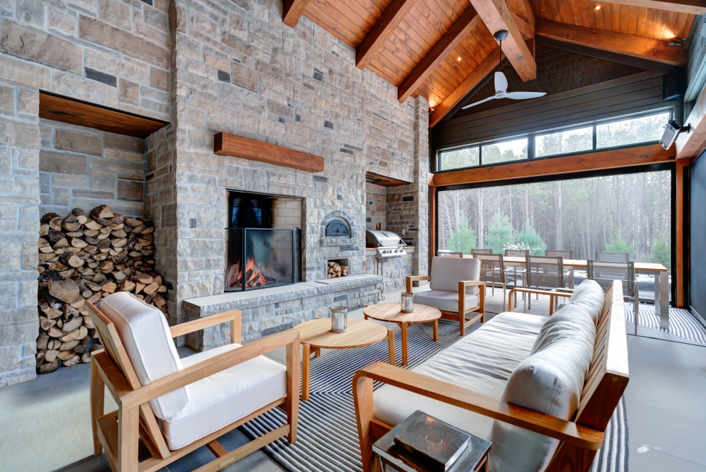 This is an example of a classic conservatory in Toronto with concrete flooring, a standard fireplace, a stone fireplace surround, a standard ceiling, grey floors and a chimney breast.