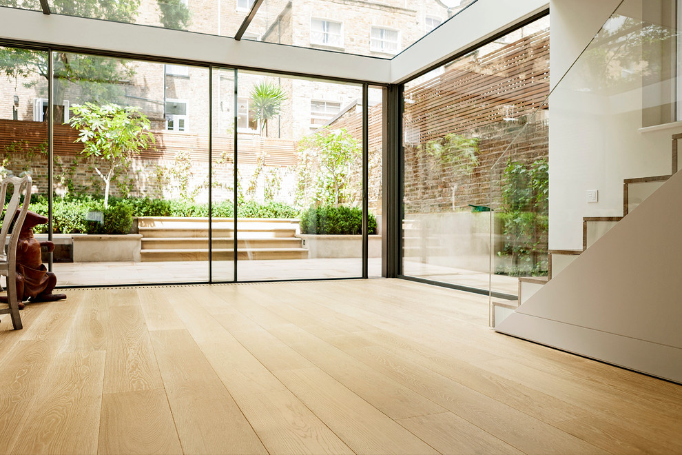 Ejemplo de galería contemporánea de tamaño medio sin chimenea con suelo de madera clara, techo de vidrio y suelo beige