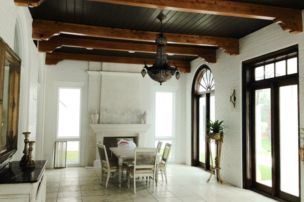 Idée de décoration pour une véranda méditerranéenne de taille moyenne avec un sol en travertin, une cheminée standard, un manteau de cheminée en pierre et un plafond standard.