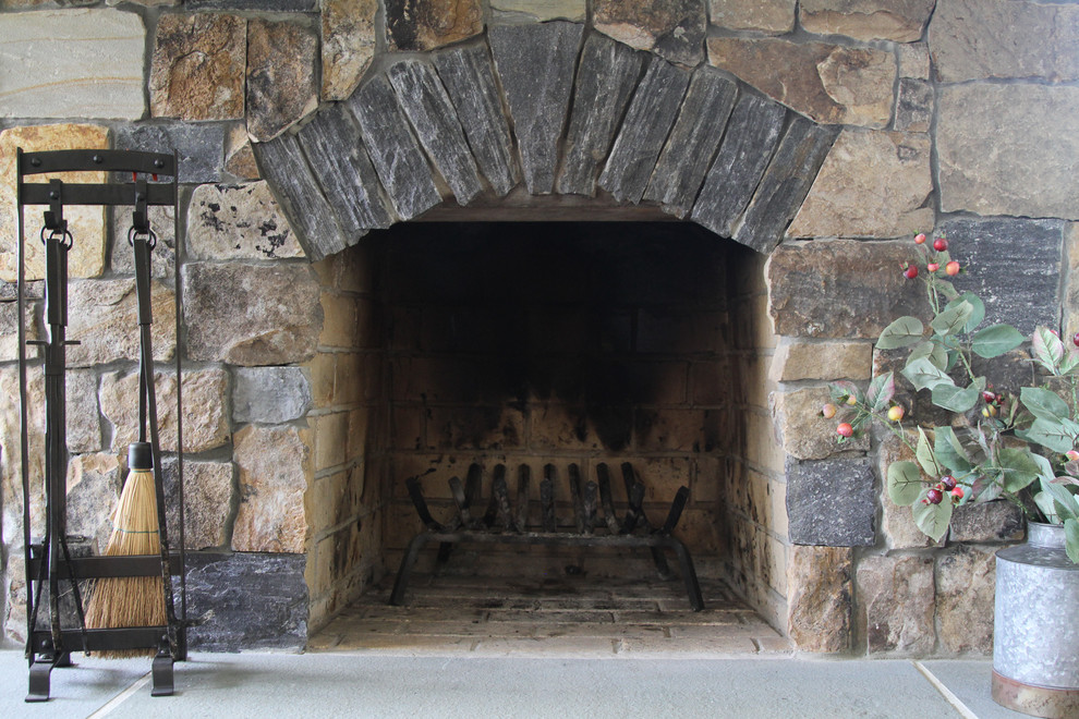 Exemple d'une grande véranda craftsman avec un sol en calcaire, une cheminée standard, un manteau de cheminée en pierre et un sol multicolore.