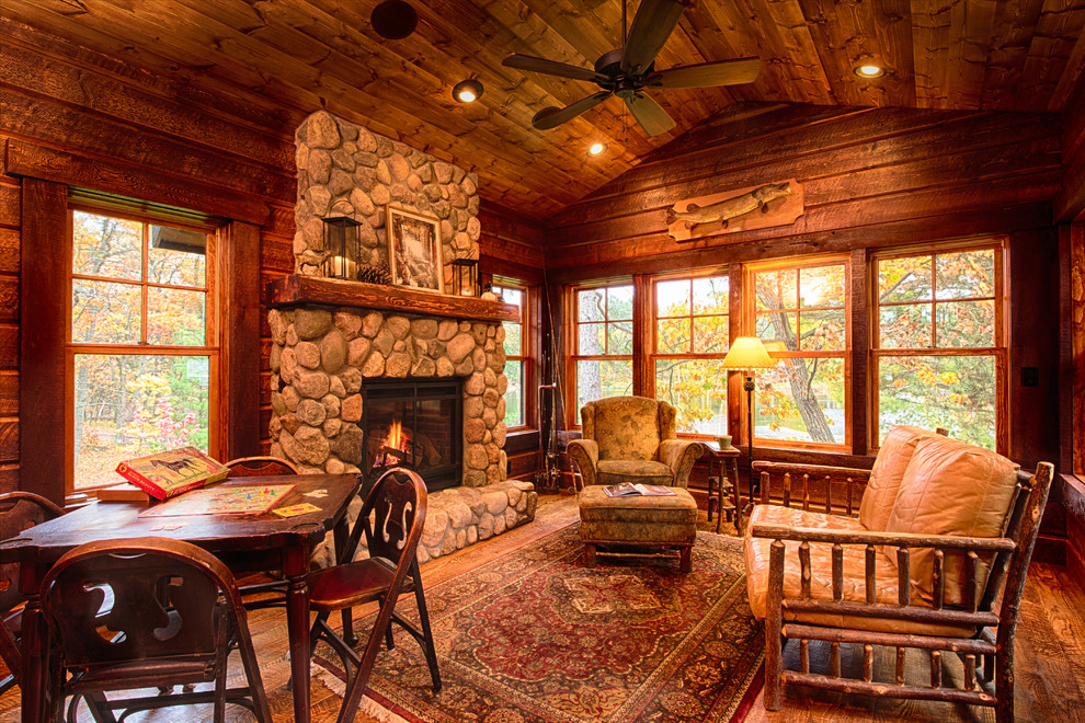 This is an example of a rustic conservatory in Minneapolis with medium hardwood flooring, a standard fireplace and a stone fireplace surround.
