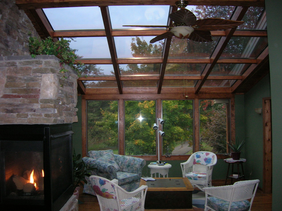 Immagine di una veranda stile rurale di medie dimensioni con parquet scuro, camino classico, cornice del camino in pietra e soffitto in vetro