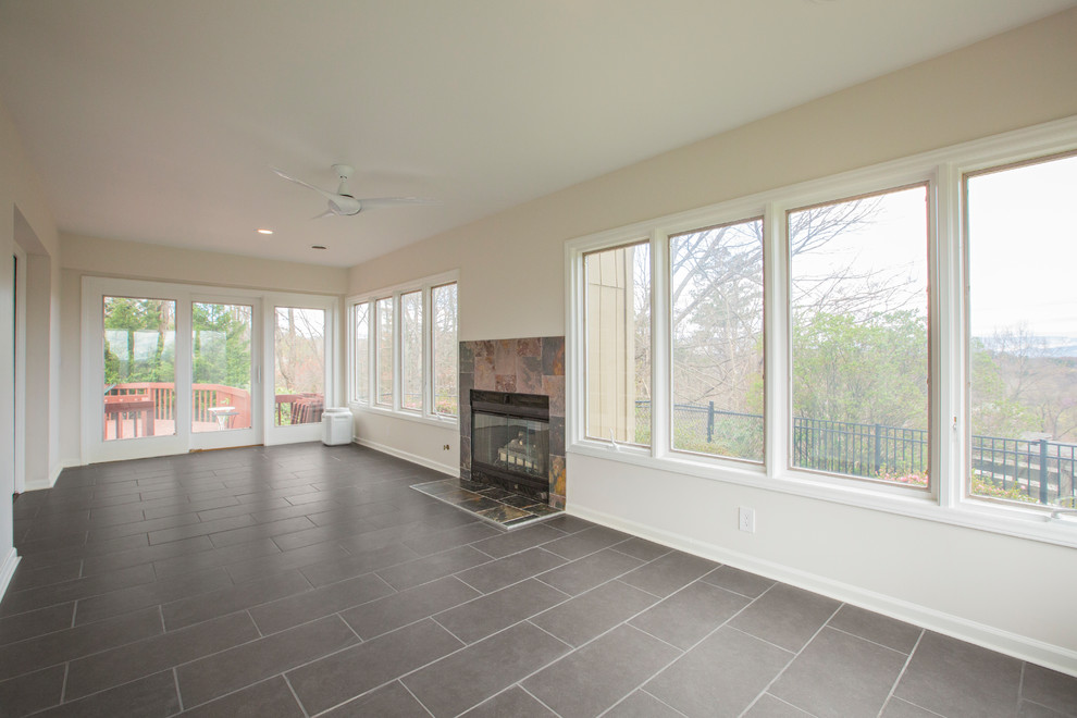Cette photo montre une grande véranda chic avec un sol en carrelage de céramique, une cheminée standard, un manteau de cheminée en carrelage, un plafond standard et un sol gris.