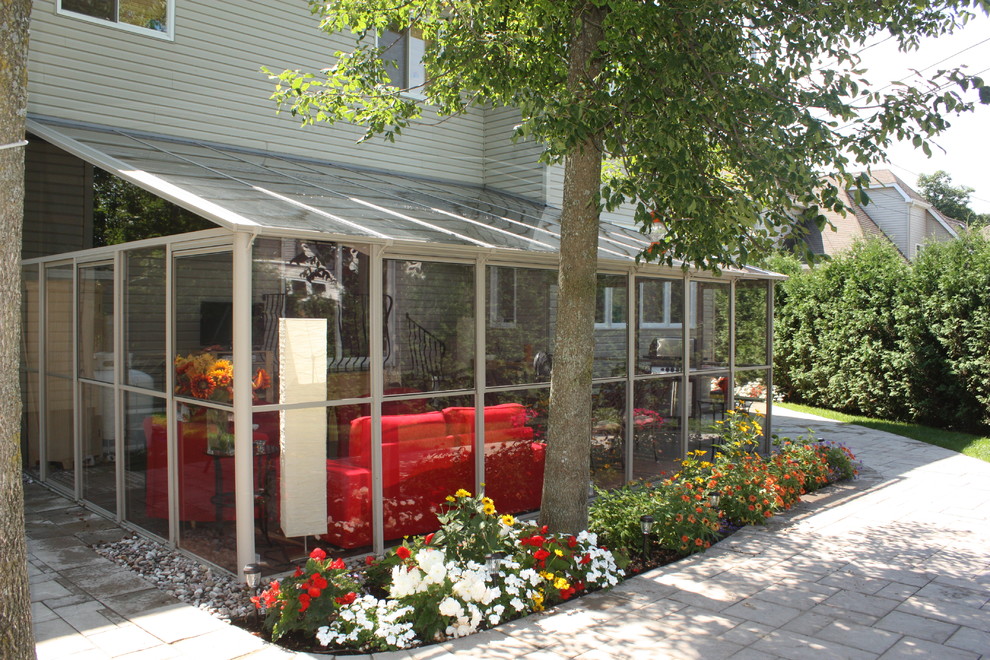 Immagine di una grande veranda minimal con pavimento in cemento e soffitto in vetro