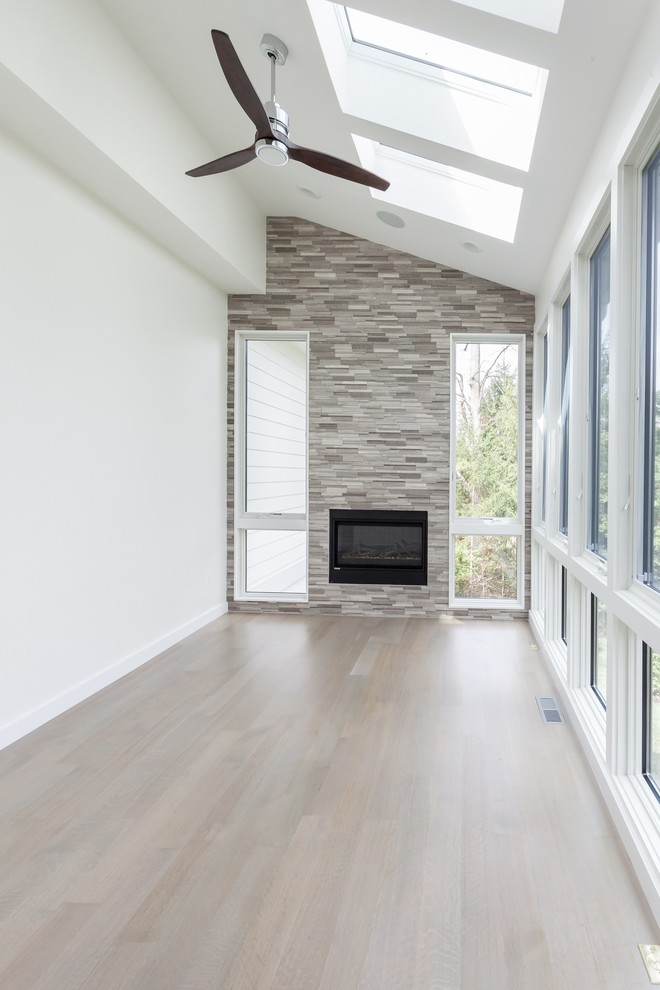 ワシントンD.C.にあるコンテンポラリースタイルのおしゃれなサンルーム (淡色無垢フローリング、横長型暖炉、タイルの暖炉まわり、天窓あり、グレーの床) の写真