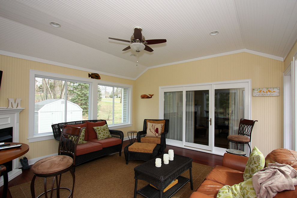 Immagine di una veranda classica di medie dimensioni con pavimento in laminato, camino ad angolo e soffitto classico