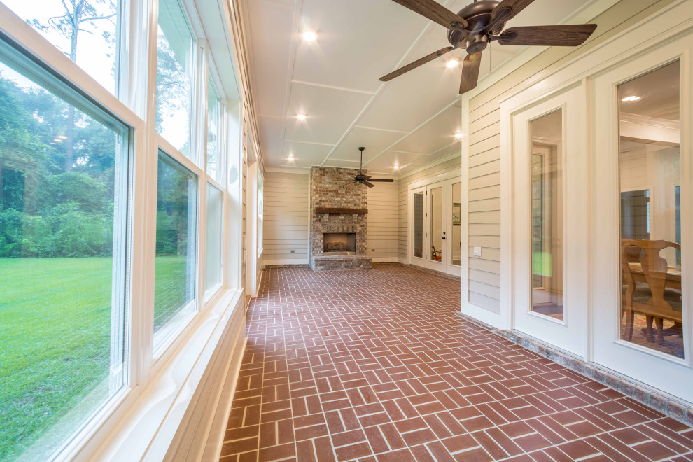 Idee per una veranda classica di medie dimensioni con pavimento in mattoni, camino classico, cornice del camino in mattoni, soffitto classico e pavimento marrone
