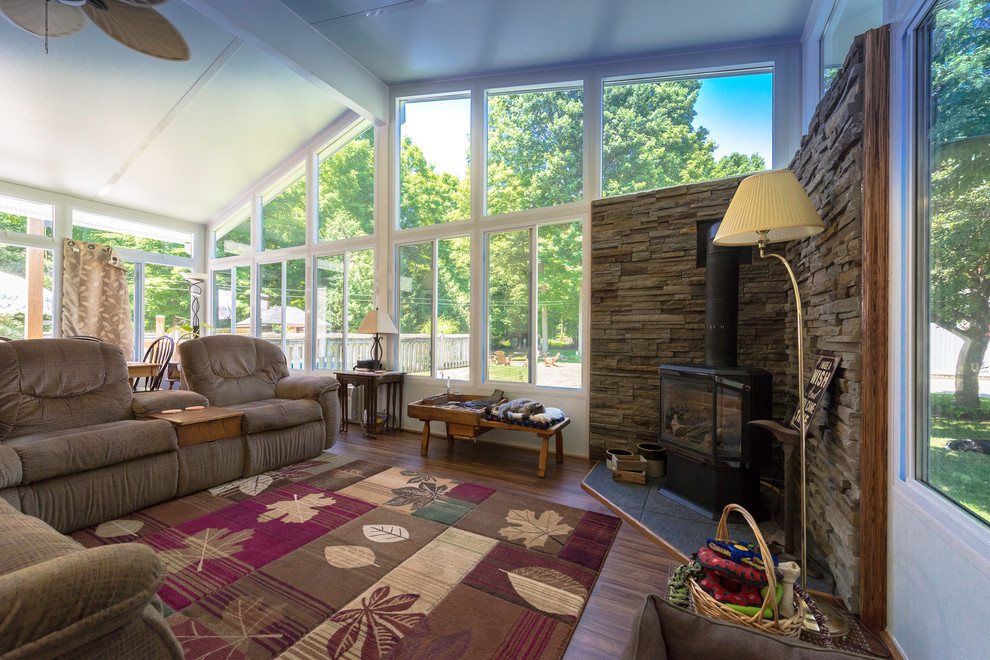 Sunroom - mid-sized transitional medium tone wood floor and brown floor sunroom idea in Other with a wood stove, a metal fireplace and a standard ceiling