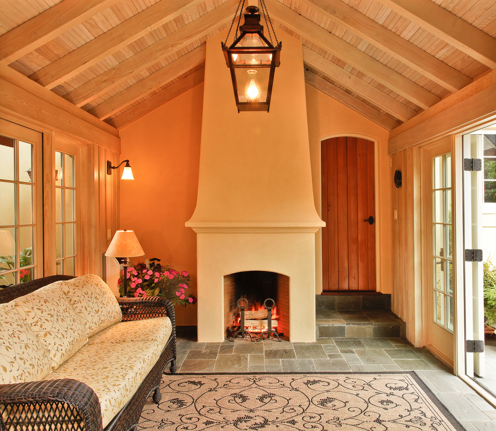 Exemple d'une véranda chic de taille moyenne avec un sol en ardoise, une cheminée standard, un manteau de cheminée en plâtre et un sol gris.