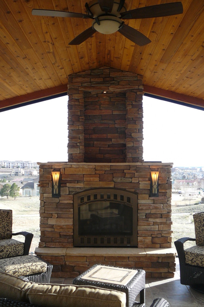 Cette photo montre une grande véranda chic avec une cheminée standard, un manteau de cheminée en pierre et un plafond standard.