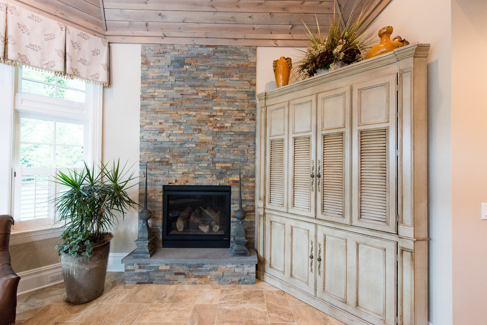 Cette image montre une grande véranda traditionnelle avec un sol en carrelage de céramique, une cheminée standard, un manteau de cheminée en pierre et un plafond standard.