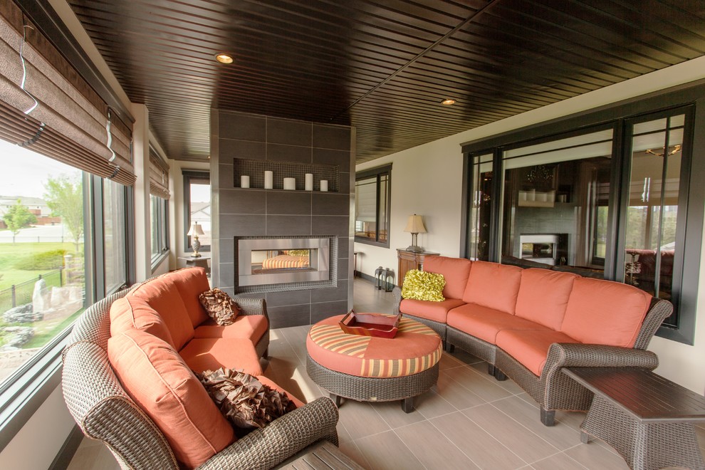 Sunroom - large traditional sunroom idea in Calgary with a two-sided fireplace and a tile fireplace