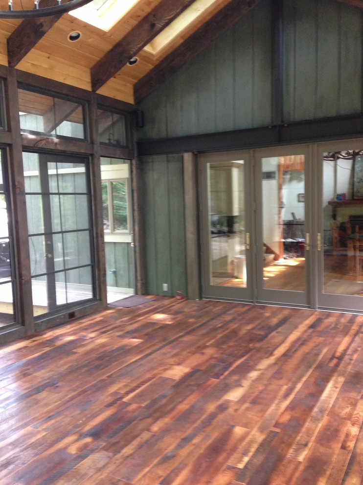 Foto di una grande veranda design con parquet scuro, stufa a legna, cornice del camino in pietra, lucernario e pavimento marrone